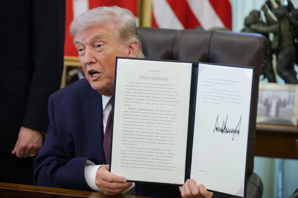 President Donald Trump holds up the signed executive order limiting mail-in voting inside the Oval Office of the White House on March 31, 2026.