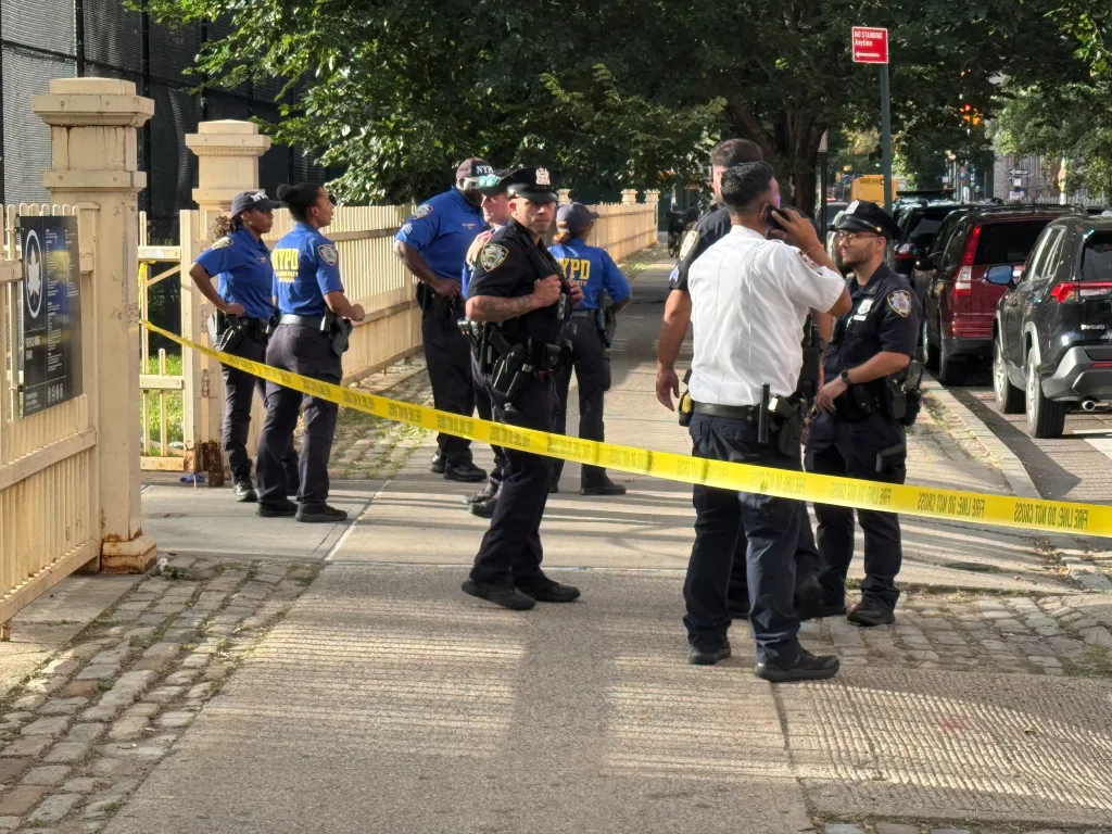 A group of New York Police Department officers behind a yellow caution tape that reads 
