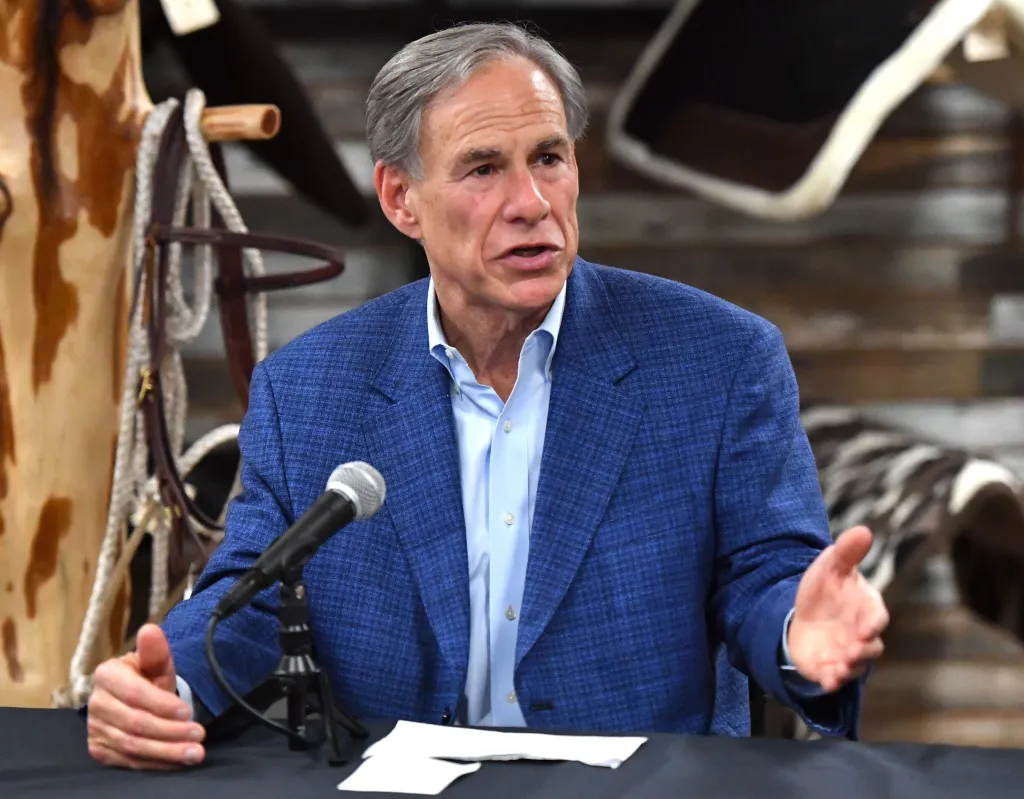 Texas Governor Greg Abbott speaking at a podium with a microphone.