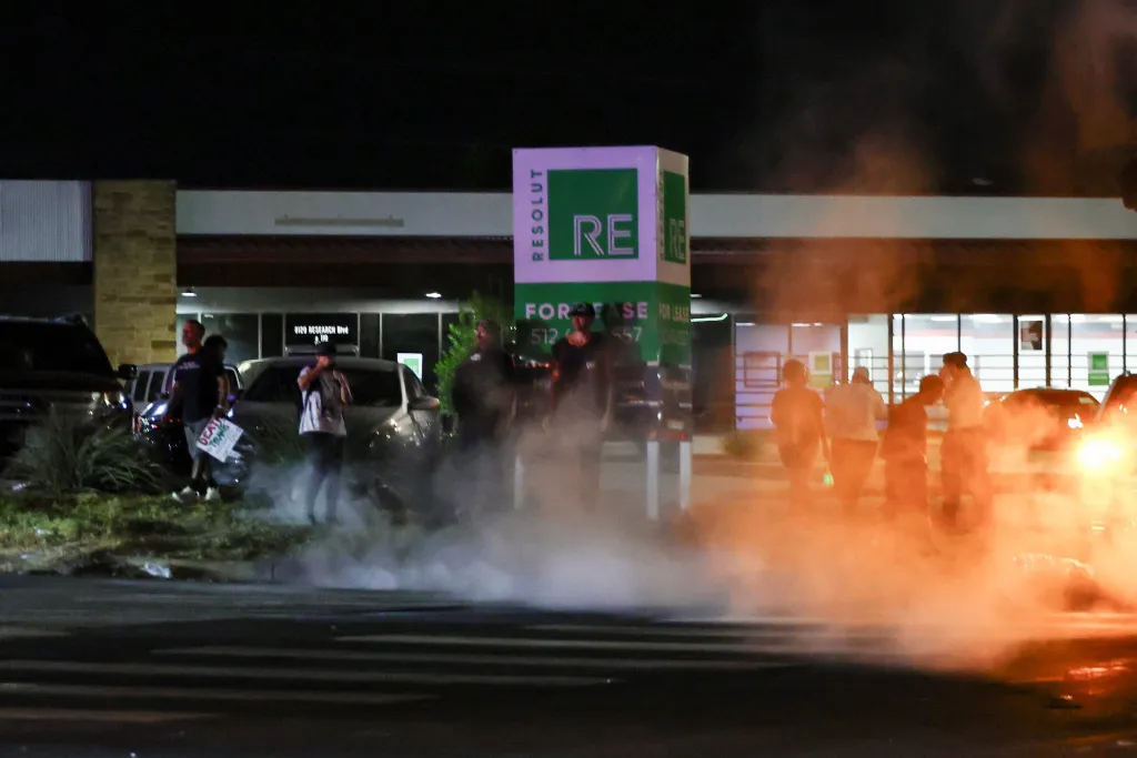 Demonstrators react to tear gas flung in their direction by police during a protest after a US Immigration and Customs Enforcement (ICE) agent shot and wounded a man, city officials said, in Austin, Texas.