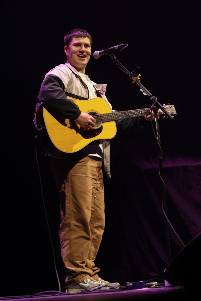 Aaron Rowe performing at Spark Arena with an acoustic guitar.