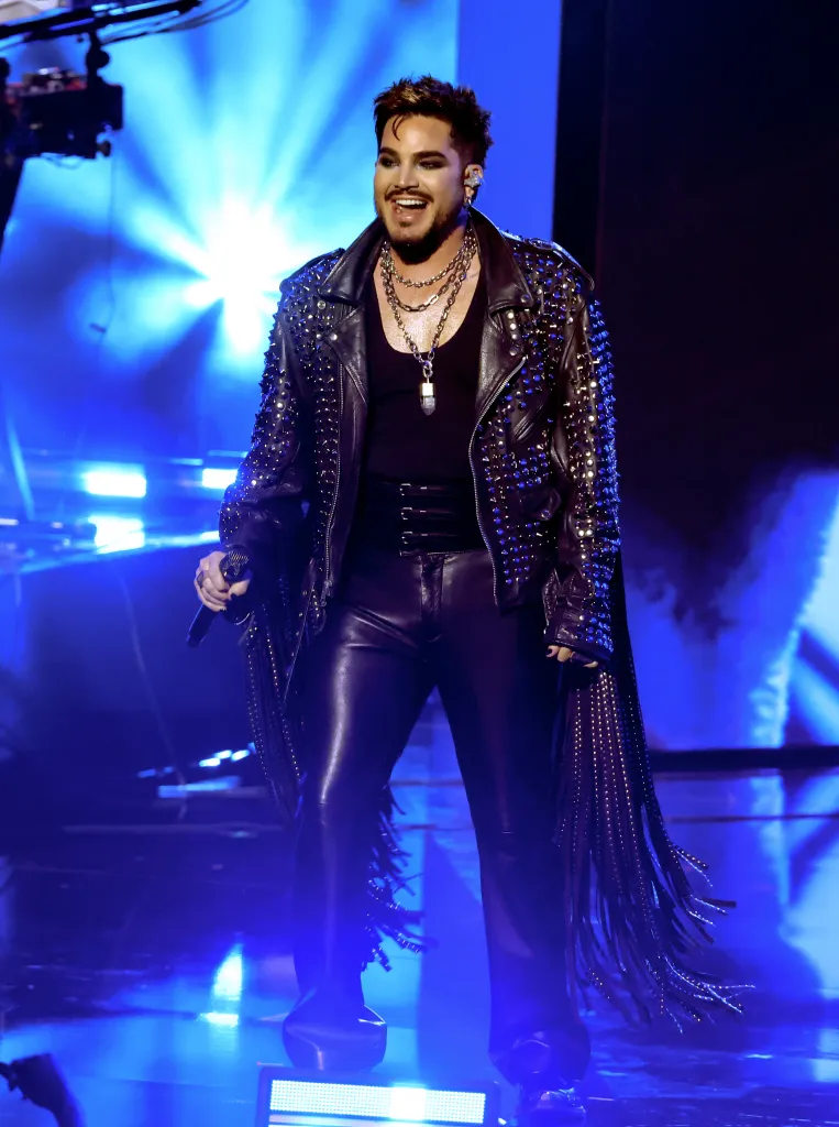 Adam Lambert performing onstage in a studded leather jacket and leather pants.