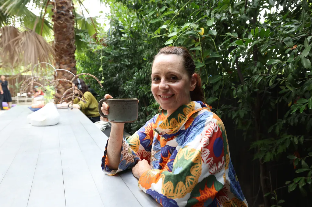 Adele Jacques smiling and holding a coffee mug at GRANADA, a community space in Los Angeles.