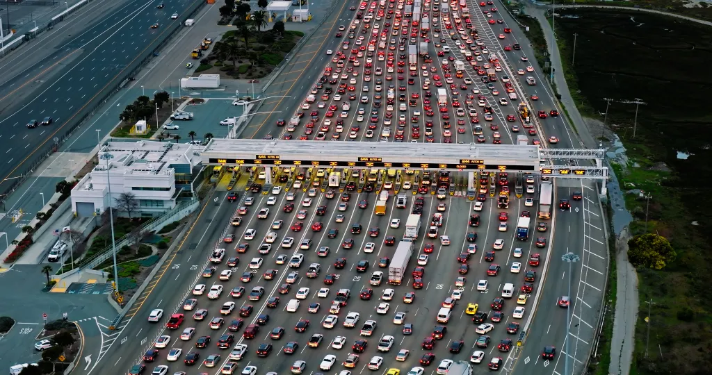 Aerial view of the Bay Bridge Toll Plaza with many cars, lights, and buildings.