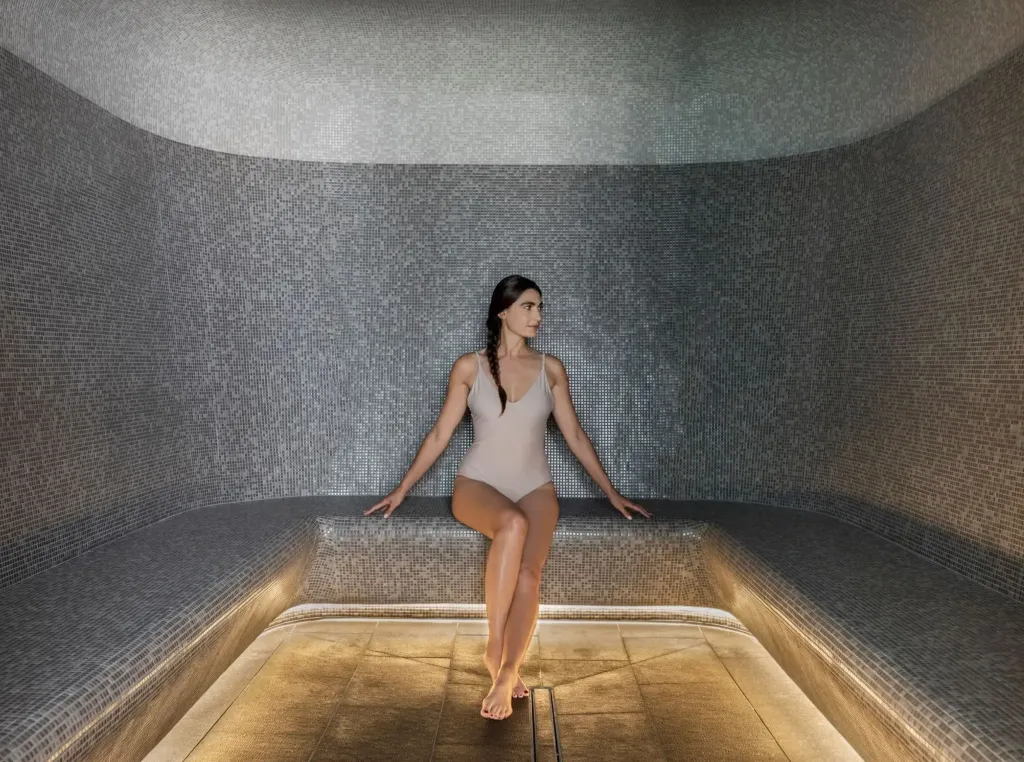 A woman in a beige swimsuit relaxing in a steam room at Alila Napa Valley.