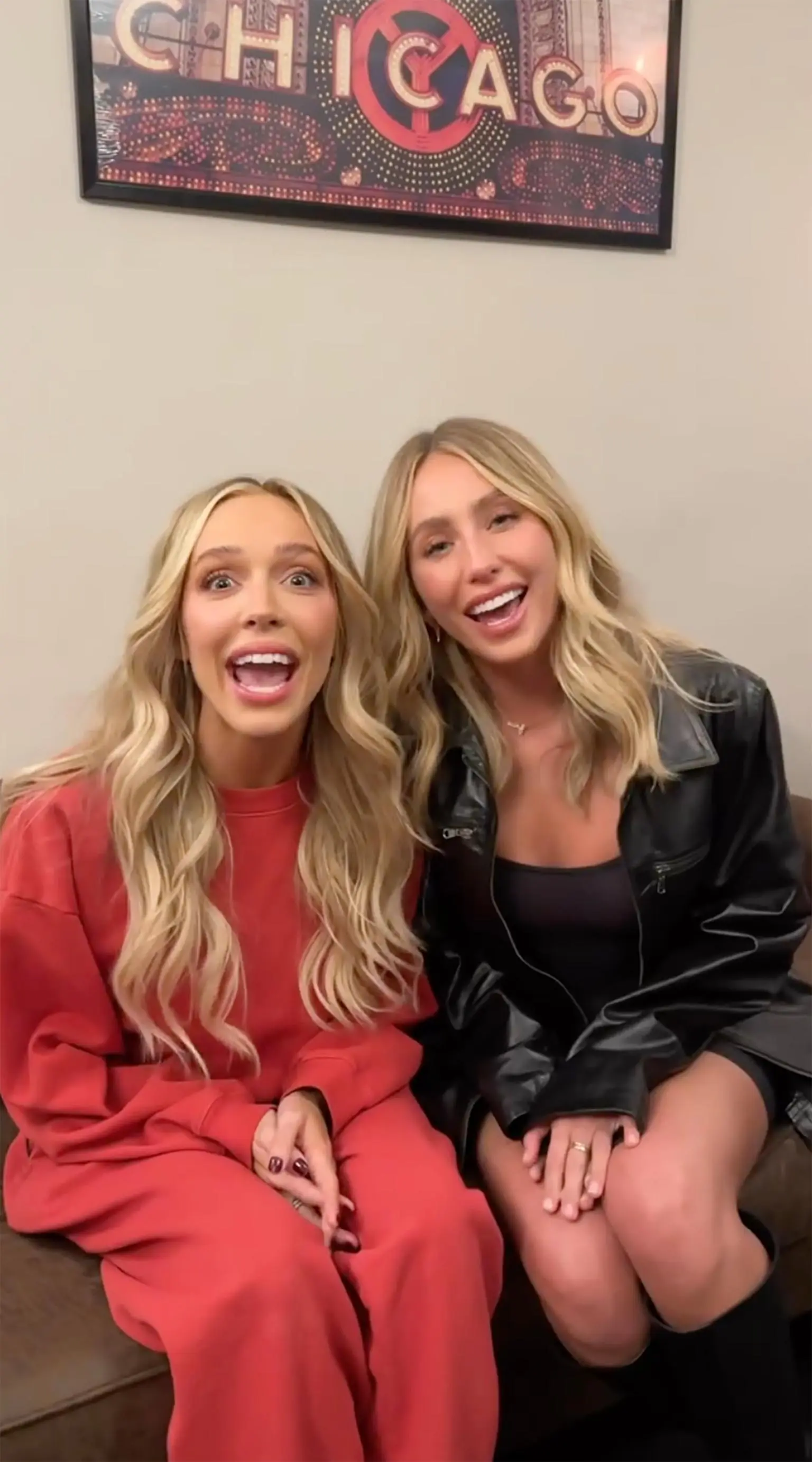 Alix Earle and Alex Cooper smiling in front of a Chicago poster.