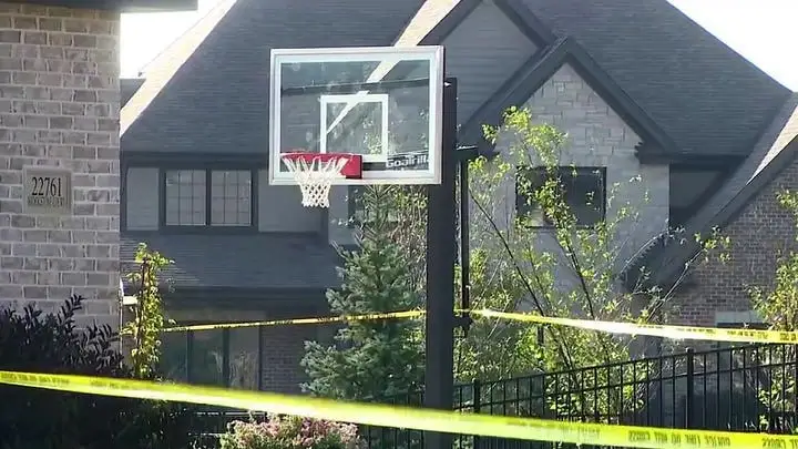 A residential property with yellow crime scene tape across the foreground, indicating a significant event.