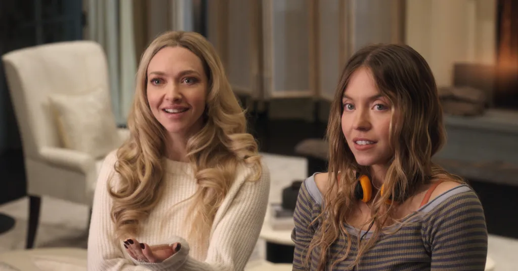 Amanda Seyfried, in a cream sweater, and Sydney Sweeney, in a grey striped sweater, in 