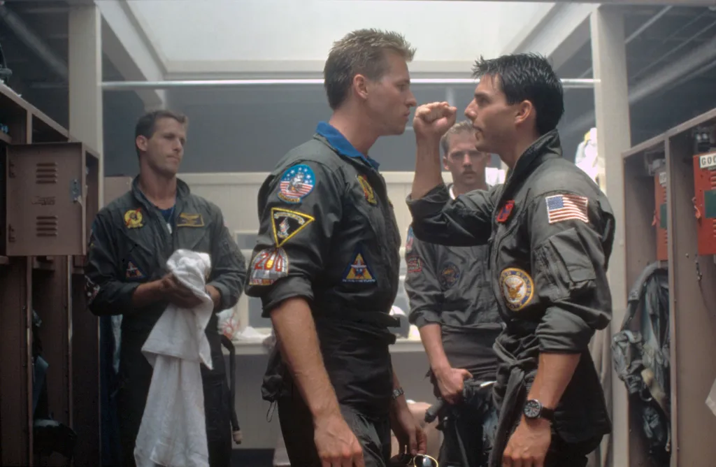 Val Kilmer and Tom Cruise, wearing khaki flight jackets, on the set of Top Gun.