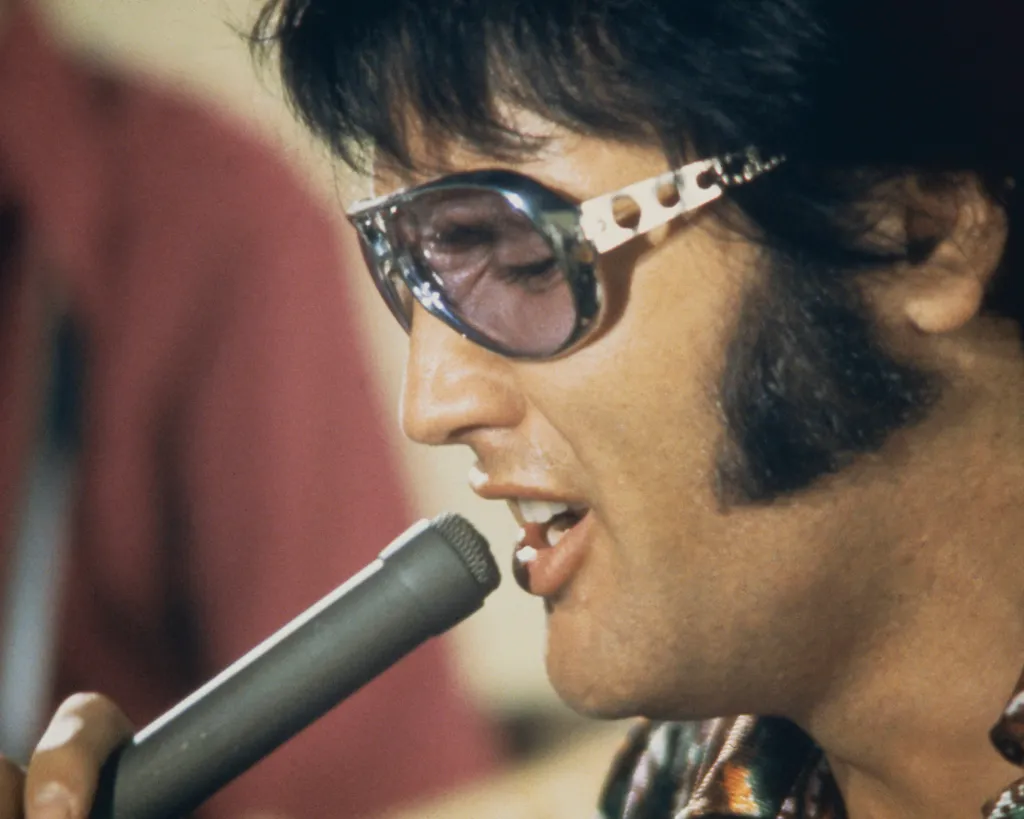Portrait of American singer and actor Elvis Presley holding a microphone.