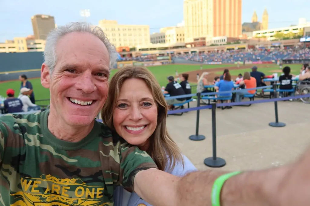 Amy Acton and a man smiling at a baseball game.