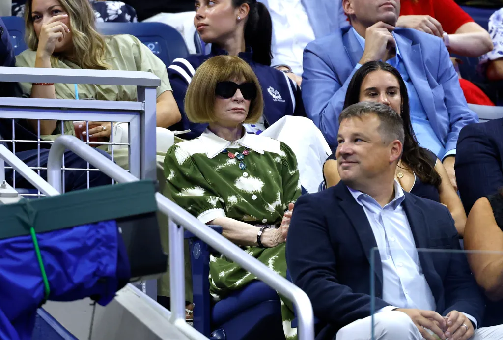 Anna Wintour in sunglasses watches a tennis match at the 2026 US Open.