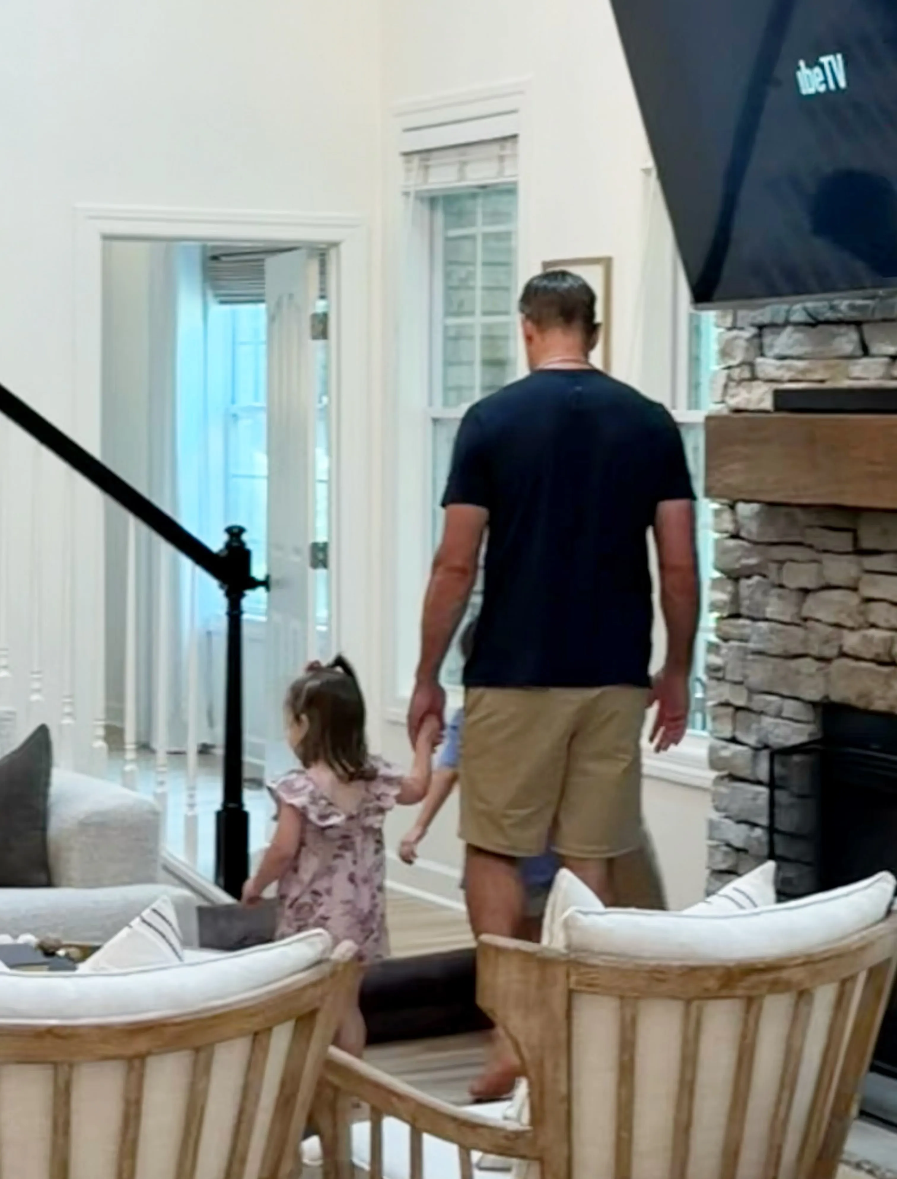 Aaron Rodgers walking hand-in-hand with a child in a living room.