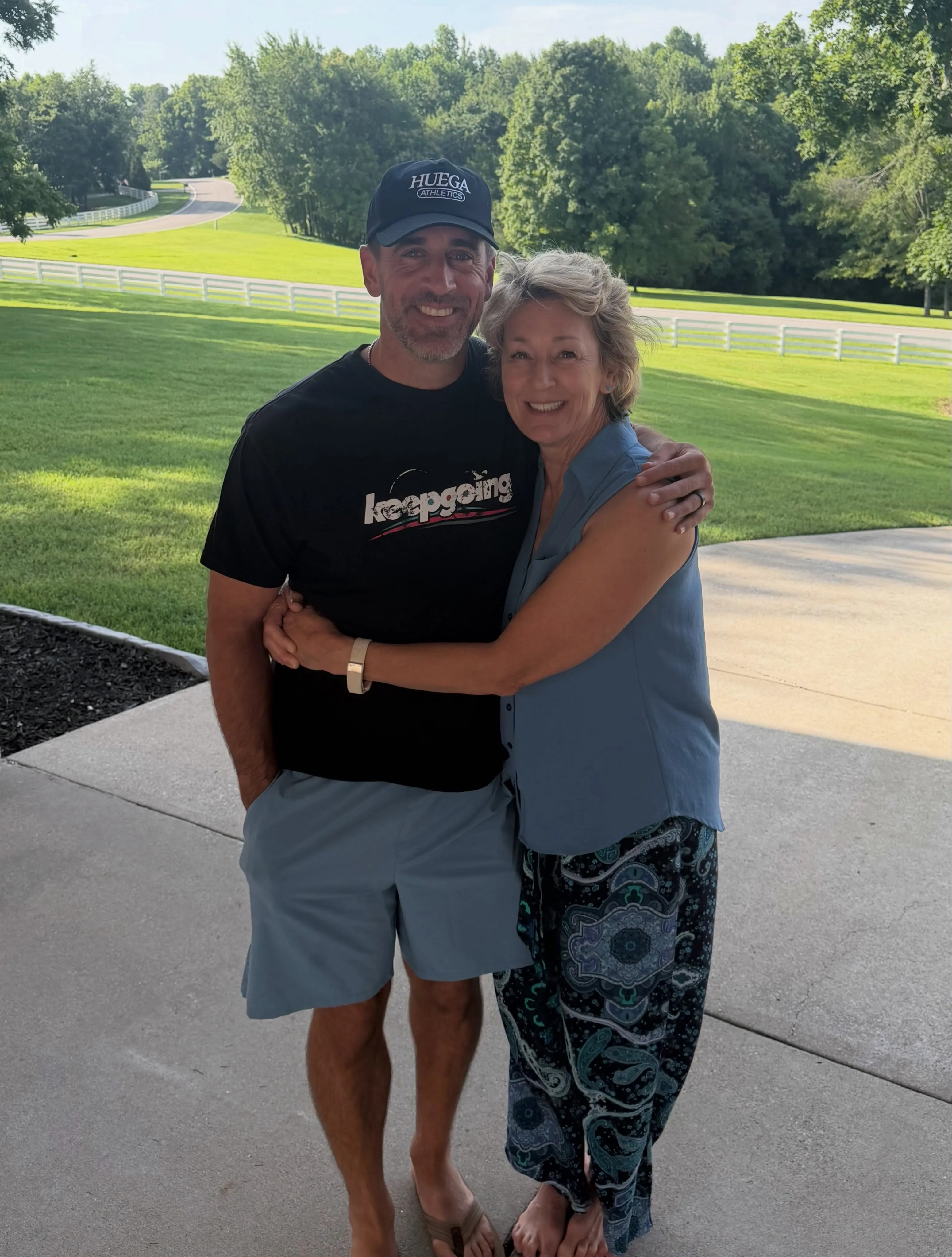 Aaron Rodgers smiling while hugging a woman.