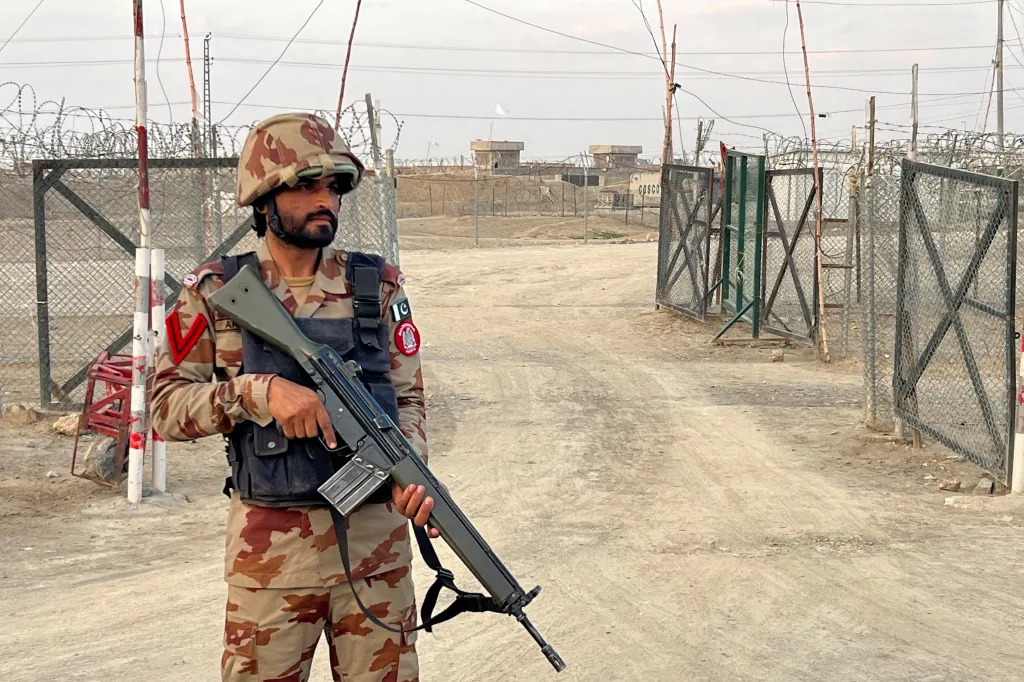 A soldier in camouflage uniform and helmet stands guard with a rifle at the deserted Friendship Gate border crossing in Chaman, Pakistan.