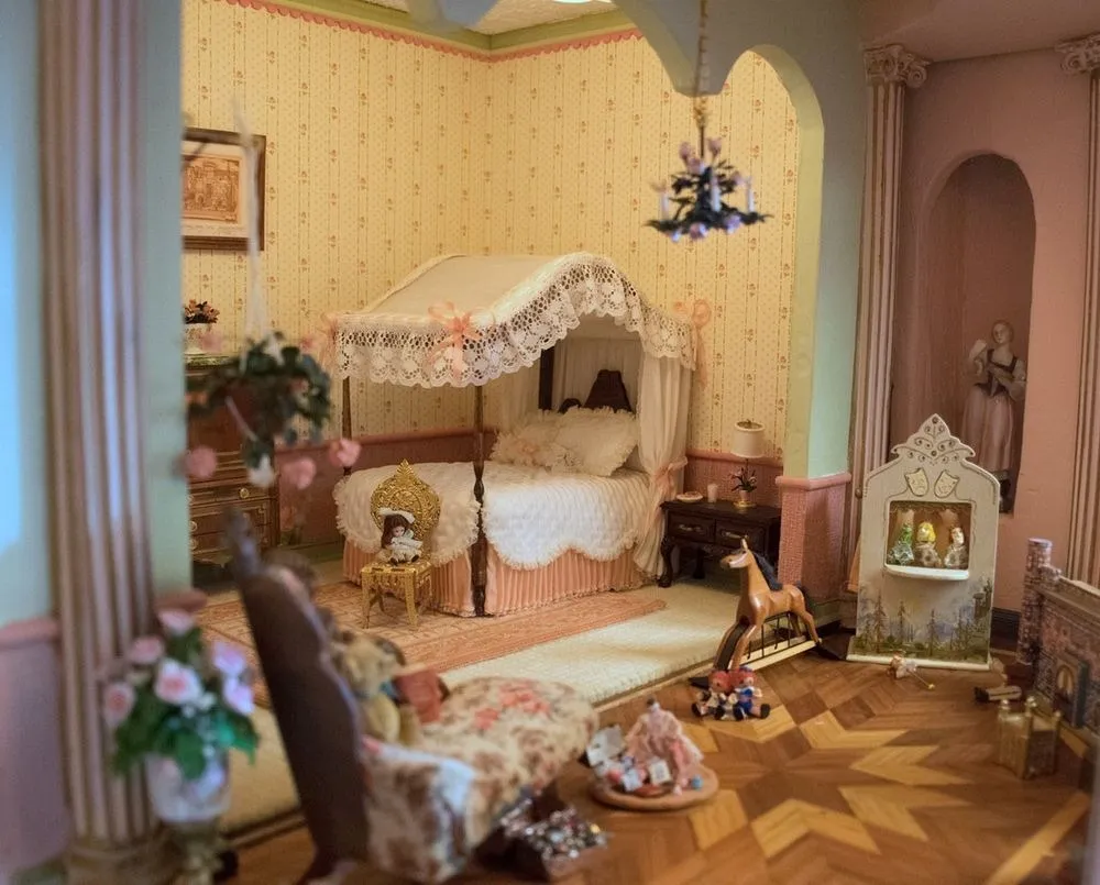 A miniature bedroom inside the Astolat Dollhouse Castle, with a canopied bed, rocking horse, and doll-sized furniture.