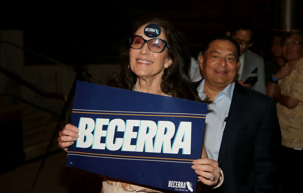 A smiling supporter holds a Becerra campaign sign at the election night party.