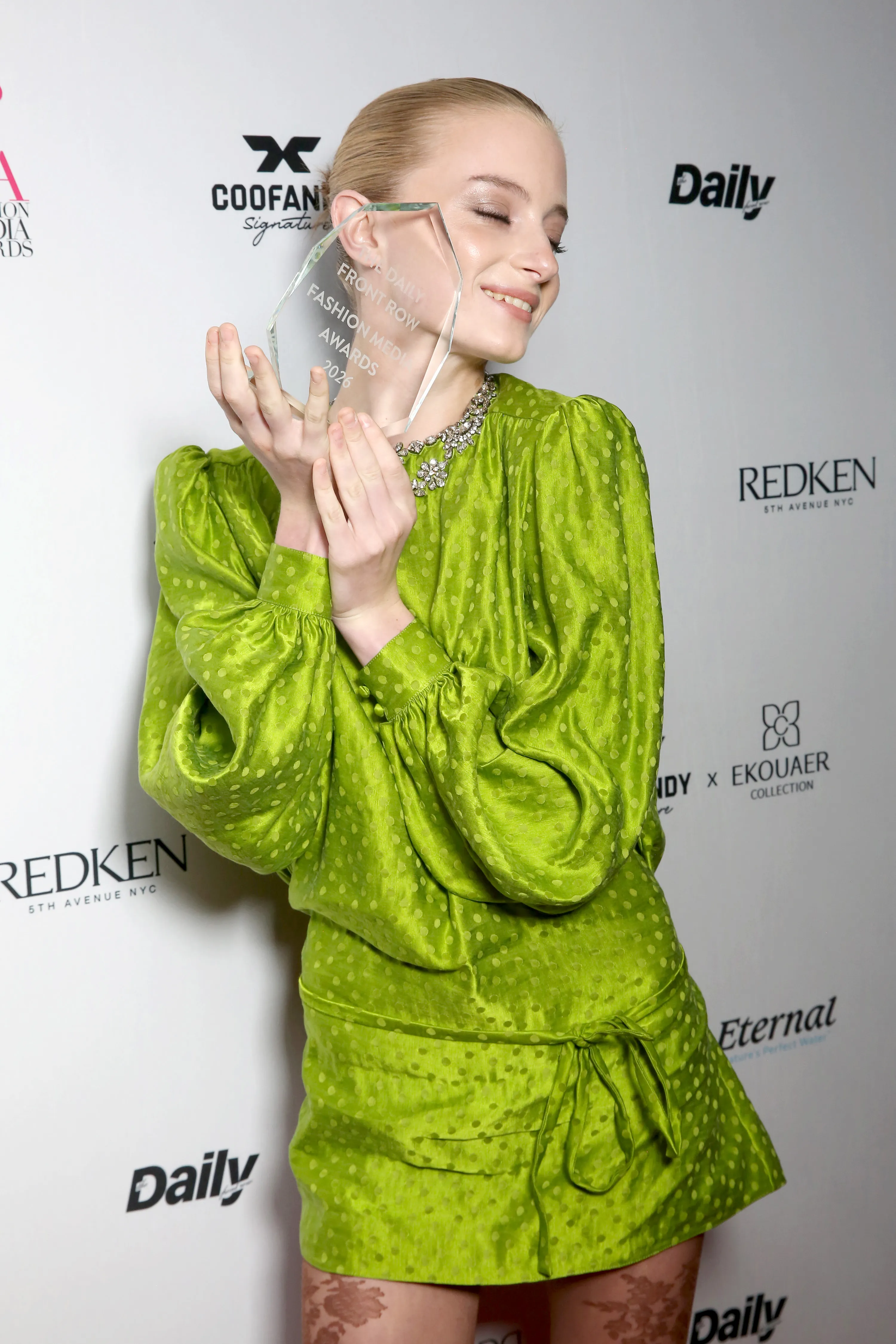Kai Schreiber holding the crystal Daily Front Row Fashion Media Awards 2026 award, dressed in a green polka dot outfit.