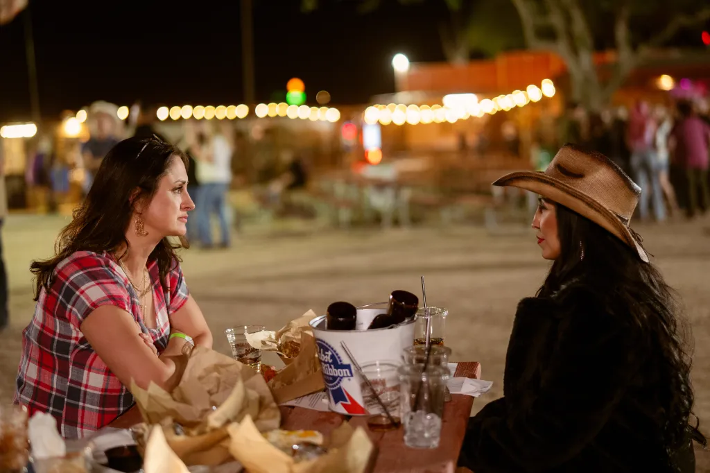 Melanie Dunmar and Rylee Baldri sitting at a picnic table at night.