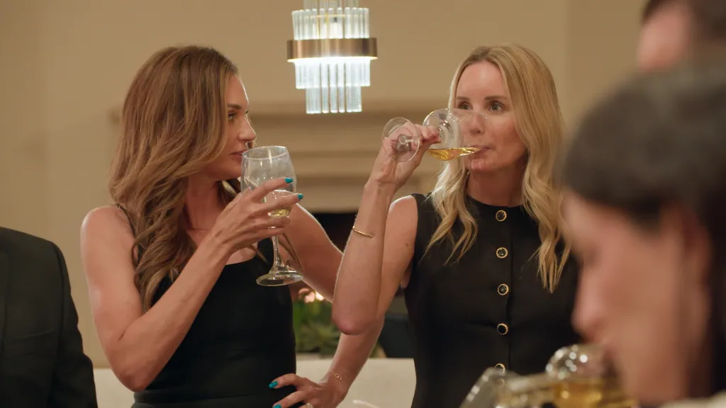 Trina Taylor and Erin Wolczik drinking from wine glasses.