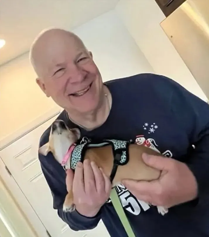 Berg, a 70-year-old hiker, smiling while holding a small dog.