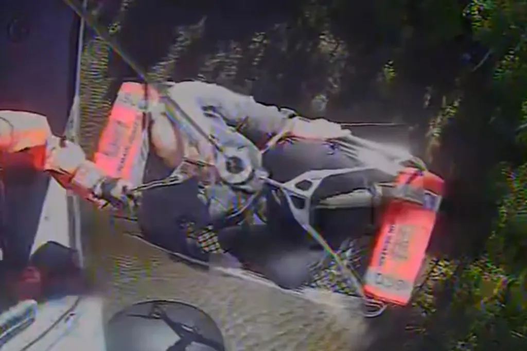 A person is being hoisted up from a forested area by a rescue team.