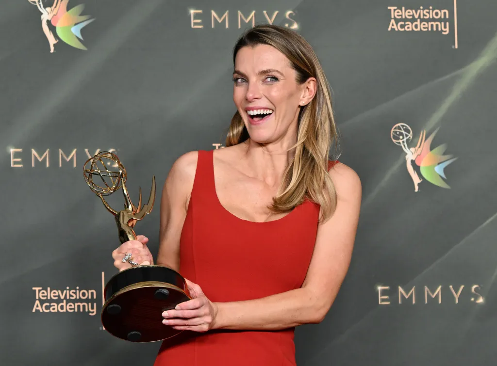 Betty Gilpin holding an Emmy award.