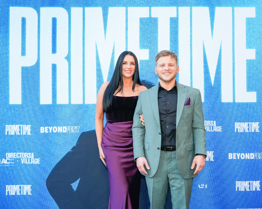 Jonathan Lipnicki and a guest posing in front of a blue 