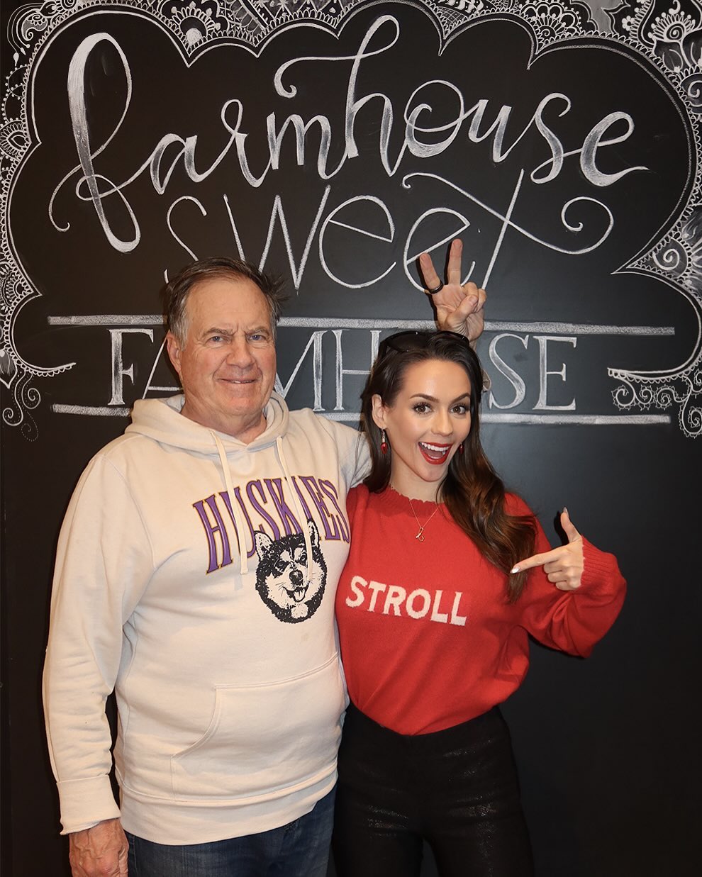 Bill Belichick and Jordon Hudson posing in front of a 