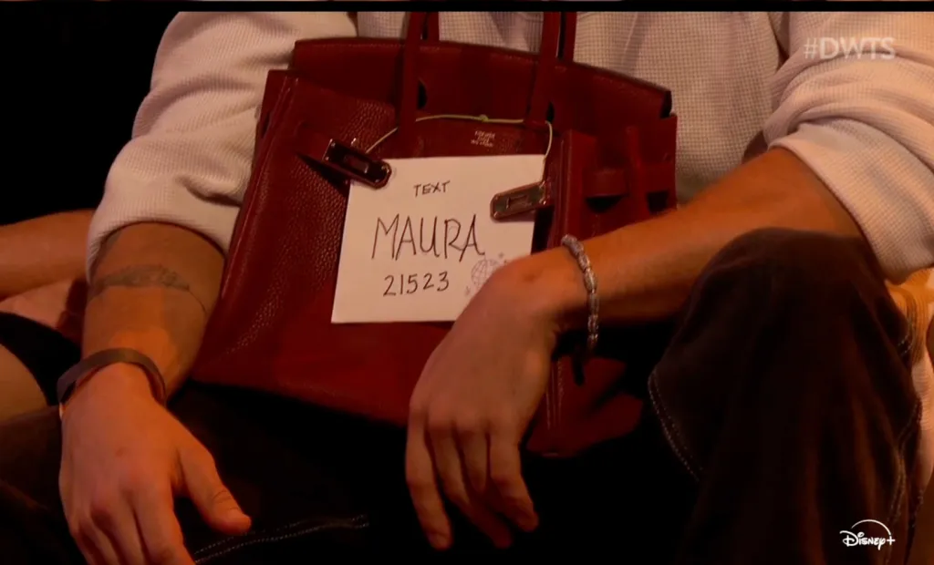 A red Birkin bag with a paper sign that reads 