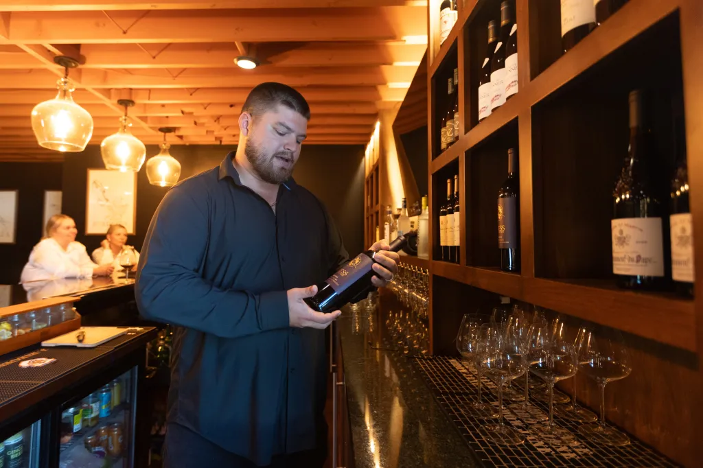 A man holds a bottle of Hess Collection Allomi cabernet sauvignon.