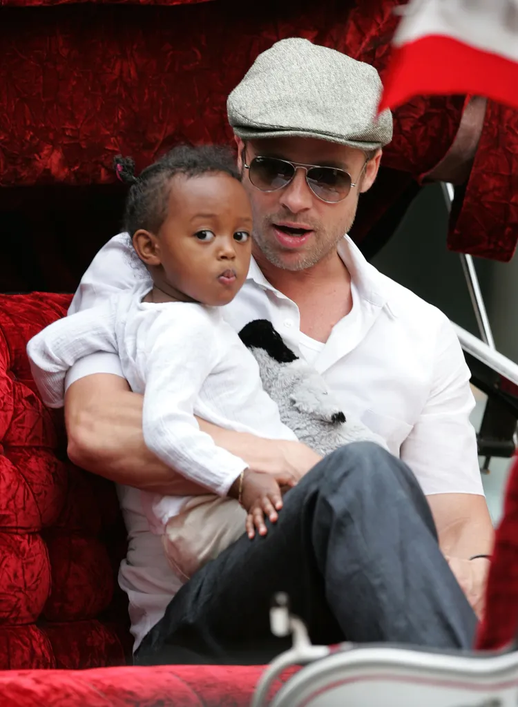 Brad Pitt holds Zahara Jolie-Pitt in a red carriage.
