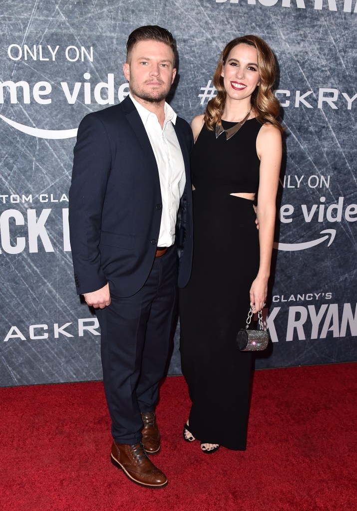 Brendan Rooney and Christy Carlson Romano pose on a red carpet in front of a branded backdrop.