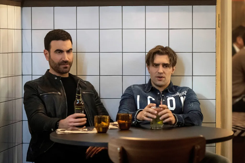 Brett Goldstein and Phil Dunster at a table with drinks in a restaurant.