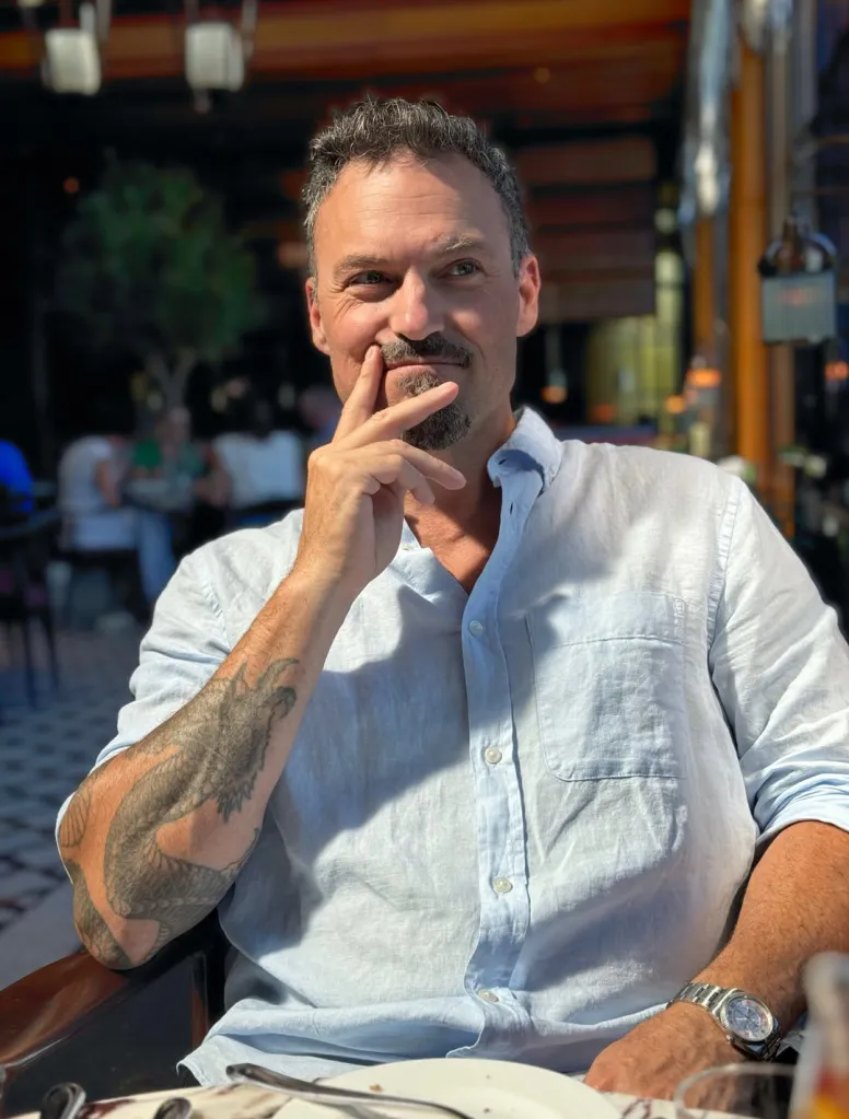 Brian Austin Green smiles while seated at a table.