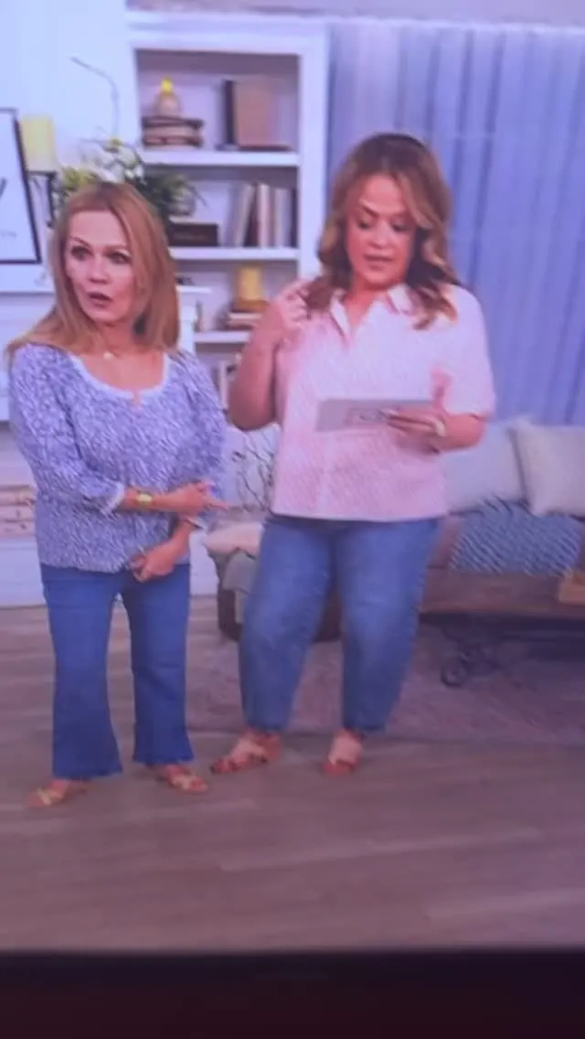 Jennie Garth and another woman stand in a room, both wearing jeans and light-colored tops.