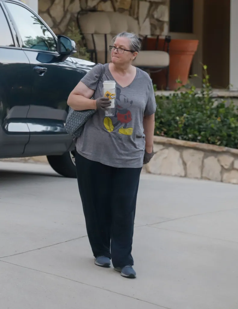 Bridget Fonda wearing a Mickey Mouse t-shirt, glasses, and holding a coffee cup while visiting a friend in Los Angeles.
