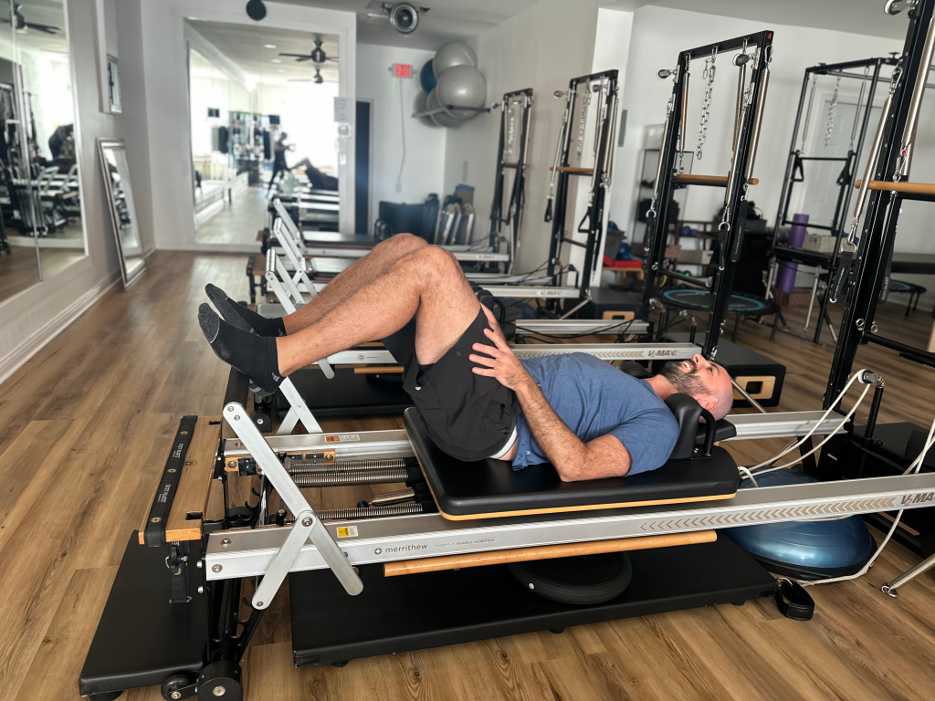 A man performing Pilates on a reformer machine during a 