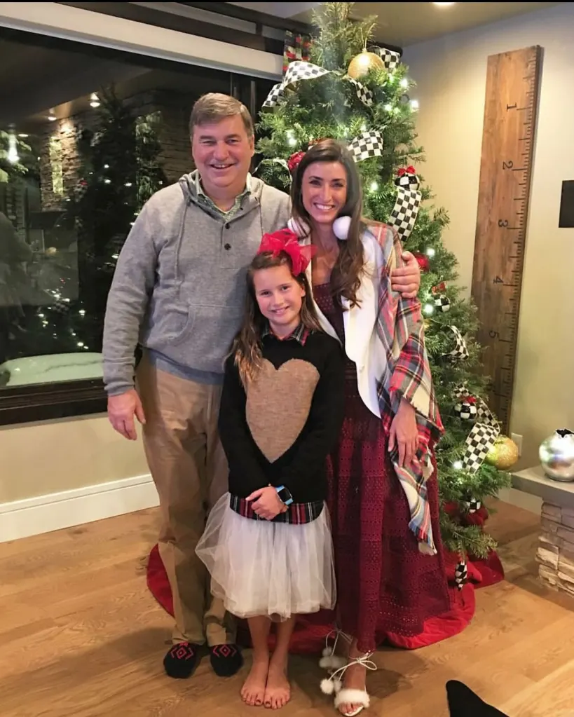 Bronwyn Newport and Todd Bradley with their daughter, standing in front of a decorated Christmas tree.