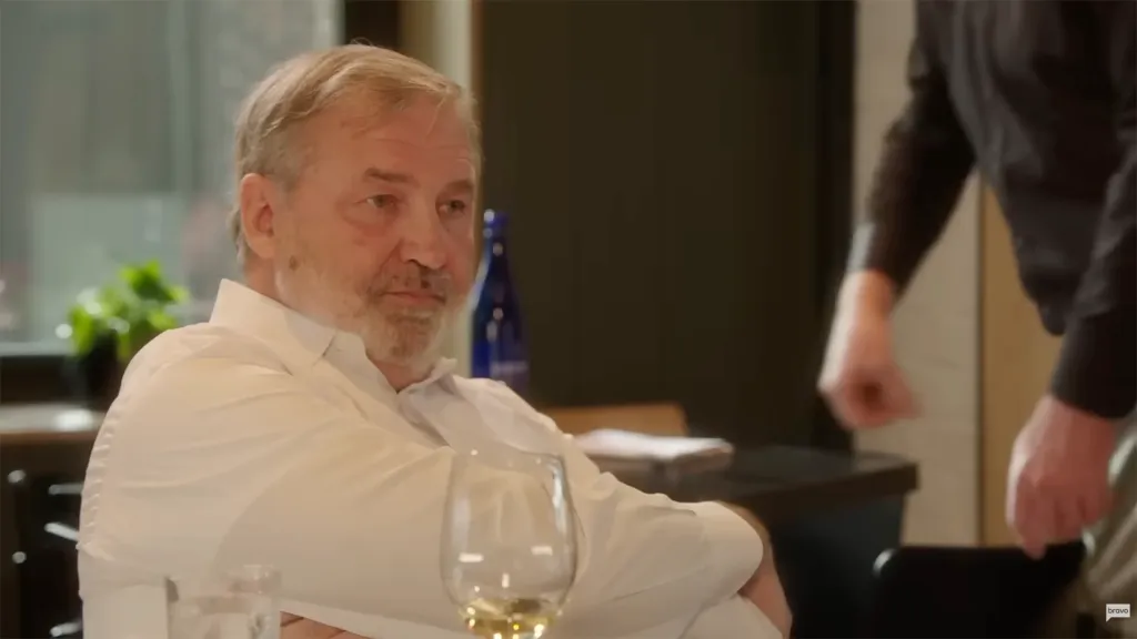 A man in a white button-up shirt looking off to the side with a serious expression.