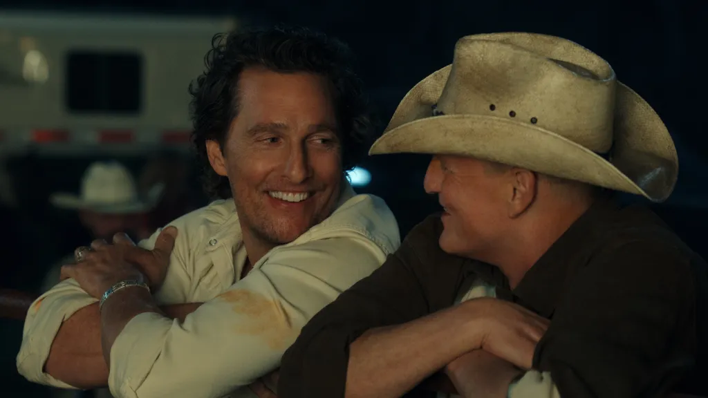 Matthew McConaughey smiling and talking with an older man in a cowboy hat.