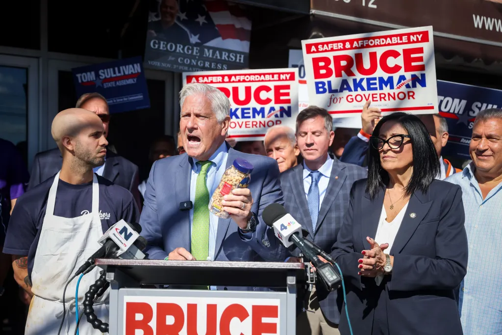 Bruce Blakeman holds a jar of peanuts while speaking at a campaign event.