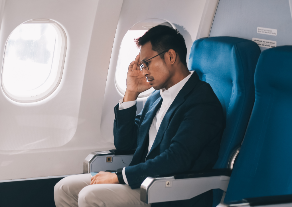 A businessman experiences headache pain or frustration on Wednesday, May 29, 2024, inside an airplane.