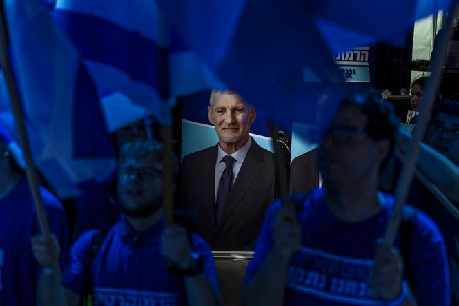 Supporters wave flags next to a portrait of Yair Golan