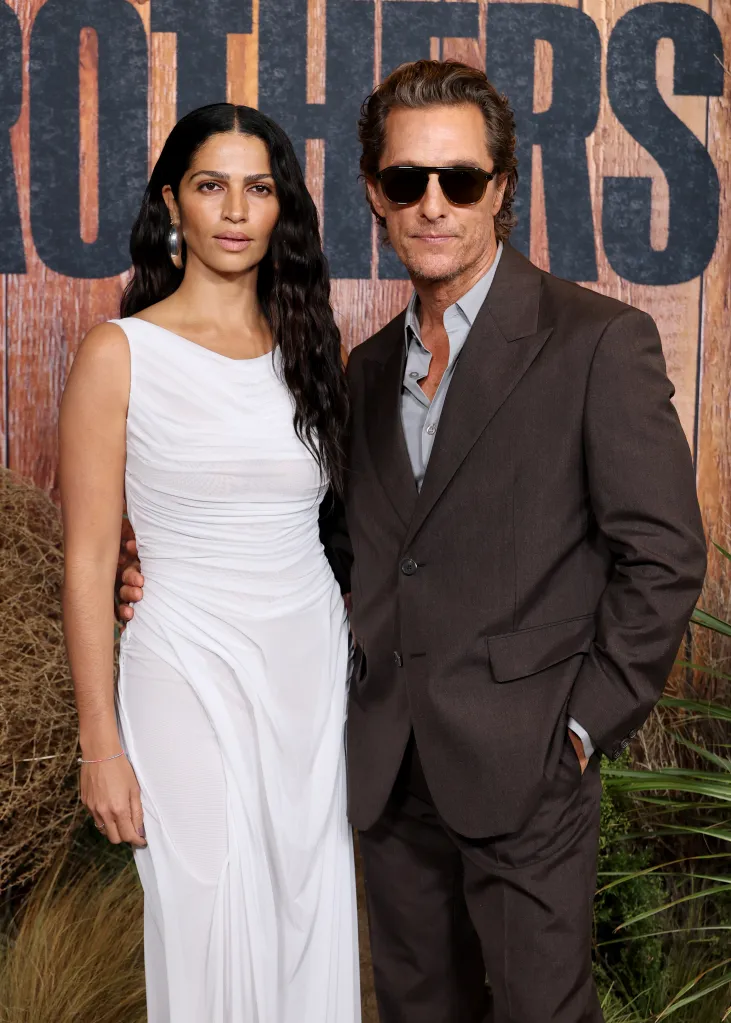Camila Alves McConaughey in a white dress and Matthew McConaughey in a brown suit and sunglasses, at the Los Angeles premiere of Apple TV's 