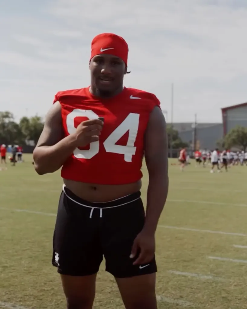 University of Houston Cougars football player Carmello Brooks in a red jersey and black shorts on a field.
