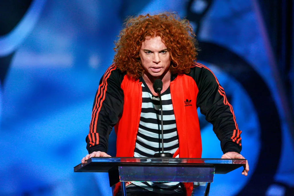 Carrot Top speaking at a podium with a microphone.