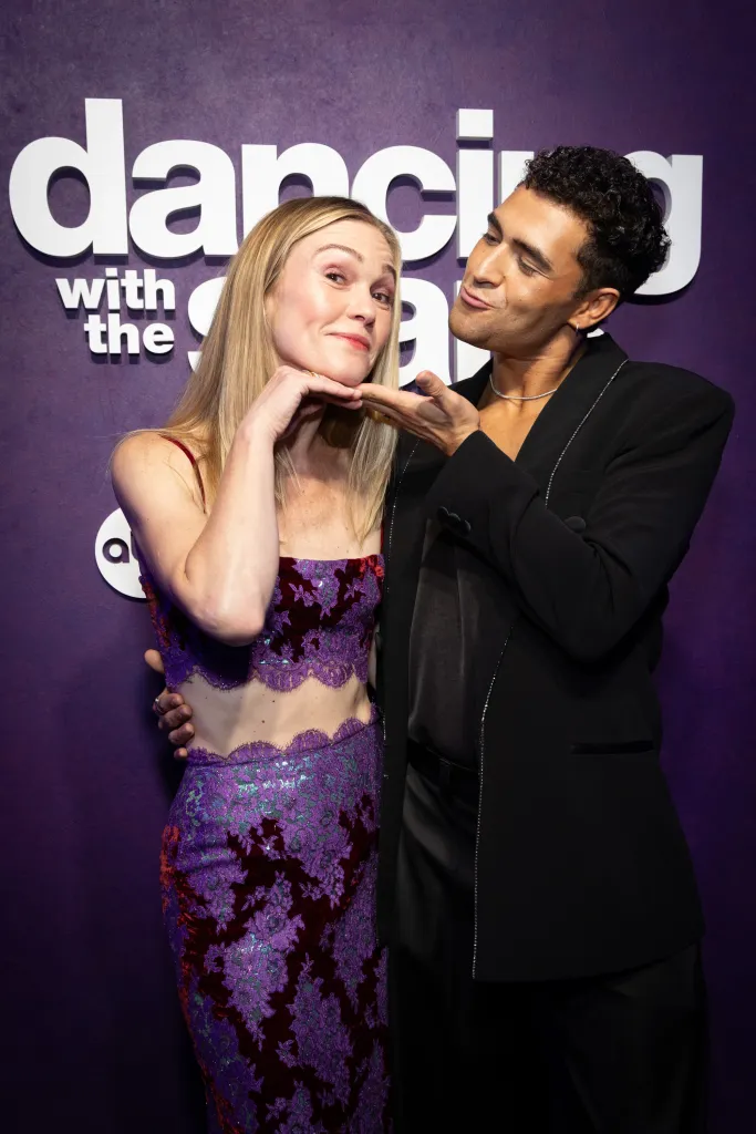 Julia Stiles and Ezra Sosa pose together playfully in front of a 