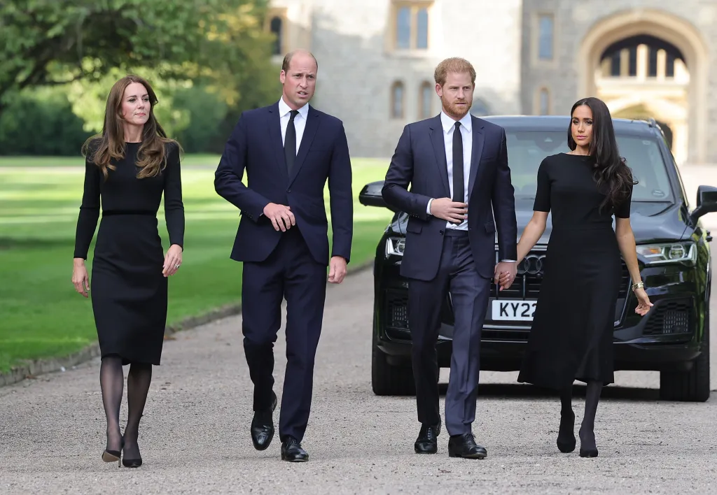 Catherine, Princess of Wales, Prince William, Prince of Wales, Prince Harry, Duke of Sussex, and Meghan, Duchess of Sussex, walk toward viewers at Windsor Castle.