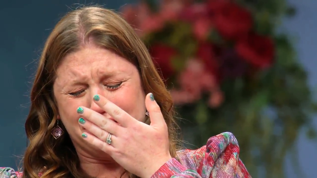 Catie crying with her hand over her mouth.